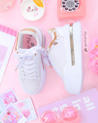 Tenis blancos suela gruesa con línea dorada y cadena al lado dorada con dijes